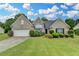 Charming single-Gathering home with a lush green lawn, well-manicured bushes, and a two-car garage at 3865 Portico Run Dr, Buford, GA 30519