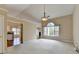 Open-concept living room with views to the kitchen and den, featuring soft carpeting and a chandelier at 3865 Portico Run Dr, Buford, GA 30519