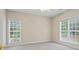 Neutral bedroom featuring carpeted floors, two bright windows, and a ceiling fan at 1253 Oakwood Pl, Loganville, GA 30052