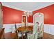 Elegant dining room with red accent wall, chandelier, and wood floors, perfect for entertaining guests at 1253 Oakwood Pl, Loganville, GA 30052