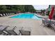 Community pool area features lounge chairs, tables and umbrellas on a sunny day at 13030 Crabapple Lake Dr, Roswell, GA 30076