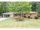 Charming brick home featuring mature landscaping, a welcoming covered carport, and a well-manicured lawn at 519 Beaver Ruin Nw Way, Lilburn, GA 30047