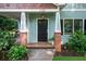 Charming front porch with brick columns and a decorative front door, enhanced by lush landscaping at 2324 Oakview Ne Rd, Atlanta, GA 30317