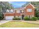 Charming two-story brick home with well-manicured lawn, mature trees, and an attached two-car garage at 2451 Broad River Pl, Ellenwood, GA 30294