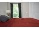 Well-lit bedroom featuring a cozy red bed, soft pillows, and a view of the outdoors through a window at 5419 S Lake Dr, Douglasville, GA 30135