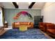 Stylish living room with a tan leather sofa, navy blue rug, black ceiling beams, and colorful wall art at 5419 S Lake Dr, Douglasville, GA 30135