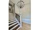 Staircase with wooden treads and white risers, complemented by a modern chandelier and wainscoting at 5419 S Lake Dr, Douglasville, GA 30135