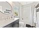 Bathroom featuring round mirror above vanity and shower/tub combo with tile surround at 6815 Berkley Rd, Cumming, GA 30040