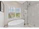 Bright bathroom features a soaking tub next to a tiled walk-in shower and large window at 6815 Berkley Rd, Cumming, GA 30040