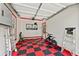 Well-lit garage with a red and black tiled floor and storage shelving and workbench area at 6815 Berkley Rd, Cumming, GA 30040