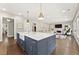 Bright, open kitchen with large island, marble counters, and stainless steel appliances with adjoining living room at 6815 Berkley Rd, Cumming, GA 30040