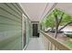 Covered front porch of a green home with a dark front door, white railings, and lush trees at 2808 Vinings Central Se Dr # 158, Atlanta, GA 30339