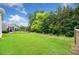 Spacious backyard featuring a lush green lawn, a wooded perimeter, and a glimpse of the home's exterior at 215 Windsor Park Dr, Woodstock, GA 30188