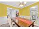 Bright dining room features yellow walls, a large wooden table and chairs, and access to other rooms at 3358 North Ct, Ellenwood, GA 30294