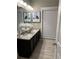 Modern bathroom featuring dual granite sinks, framed art, and tiled flooring at 2709 Ratby Ne Ln, Conyers, GA 30013