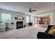 Open-concept layout with cozy living room adjacent to the kitchen featuring fireplace, ceiling fan, and bright windows at 347 Cobblestone Court, Hampton, GA 30228