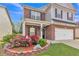 Well-kept front yard with colorful flowerbeds, a covered porch, and a two-story brick and siding home at 911 Sonoma Dr, Lawrenceville, GA 30045