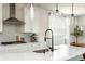 Modern kitchen showcasing an island with sink, gas range and hood, with gray backsplash and stylish lighting at 5025 Bryce Ln, Cumming, GA 30040