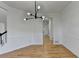 Open dining room boasts hardwood floors, white walls, and contemporary chandelier, with access to staircase and kitchen area at 1285 Cedar Brook Dr, Lawrenceville, GA 30043