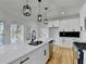 Bright kitchen boasts stainless appliances, black hardware, white cabinets, granite counters, and modern lighting at 1285 Cedar Brook Dr, Lawrenceville, GA 30043