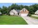 Inviting brick home featuring a well-maintained lawn and a convenient two-car garage and tree lined backyard at 1290 Silverstone Trl, Jonesboro, GA 30238