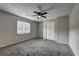 This bedroom features neutral walls, plush carpet, a ceiling fan, and a window at 4090 Mark Todd Ct, Hoschton, GA 30548