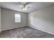 A neutral bedroom featuring plush carpet, a ceiling fan, and a window for natural light at 4090 Mark Todd Ct, Hoschton, GA 30548