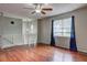 Bright living room with wood floors, a ceiling fan, and natural light from the large window at 4090 Mark Todd Ct, Hoschton, GA 30548