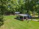 Expansive backyard featuring a covered patio, lush green lawn, storage building and mature trees at 100 Chadwick Pl, Villa Rica, GA 30180
