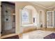 Elegant bathroom featuring a soaking tub under a decorative window and a separate glass-enclosed shower at 179 Worthington Way, Jonesboro, GA 30236