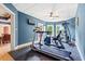 Bright exercise room features modern fitness equipment, blue walls, and access to the backyard at 179 Worthington Way, Jonesboro, GA 30236