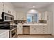 Cozy kitchen featuring white cabinets, stainless steel appliances, and a mosaic tile backsplash at 248 Riverview Trl, Roswell, GA 30075