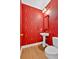 Powder room with red patterned wallpaper, pedestal sink, and matching framed mirror at 2021 Cockrell Pointe Nw, Kennesaw, GA 30152