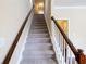 Carpeted staircase with wood banister leading to the upper level of the home at 4400 Village Field Pl, Suwanee, GA 30024