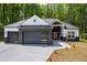 Charming home showcasing a black brick facade, modern garage doors and a well-manicured lawn at 632 Hunters Cove Ln., Loganville, GA 30052