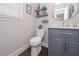 Modern powder room with blue vanity, round mirror, decorative shelves and wood-look vinyl flooring at 7533 Mason Falls Dr, Winston, GA 30187