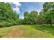A large, grassy backyard surrounded by lush trees and a bright blue sky at 1810 King Mill Rd, Mcdonough, GA 30252