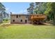 Exterior rear view of a brick home and a large backyard with a wood deck at 530 Village Green Sw Ct, Lilburn, GA 30047