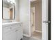 Bright bathroom featuring white vanity, new fixtures, and a view into another room with wood-look flooring at 530 Village Green Sw Ct, Lilburn, GA 30047