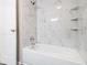 Modern bathroom featuring a tub with white marble-style tiling and built-in shelves at 530 Village Green Sw Ct, Lilburn, GA 30047