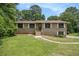 Charming brick home featuring a well-maintained lawn and classic architectural details and mature trees at 530 Village Green Sw Ct, Lilburn, GA 30047
