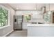 Modern kitchen with stainless steel appliances, white cabinets, island, and ample natural light from large windows at 530 Village Green Sw Ct, Lilburn, GA 30047