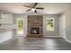 Open-concept living space with brick fireplace, wood-look floors, and a door that leads to outdoor deck at 530 Village Green Sw Ct, Lilburn, GA 30047
