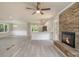 A spacious living room with a brick fireplace, ceiling fan, and seamless transition to a modern kitchen at 530 Village Green Sw Ct, Lilburn, GA 30047