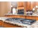 Close up of gas cooktop in kitchen with granite countertops and wood cabinets at 1090 Crown River Pkwy, Mcdonough, GA 30252