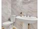 Elegant bathroom featuring white marble walls, a pedestal sink, and modern fixtures at 1952 Skidmore Cir, Lawrenceville, GA 30044