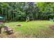 Private backyard with lush lawn, stone fire pit, mature trees, and play equipment at 2093 Kolb Ridge Sw Ct, Marietta, GA 30008