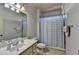 Bright bathroom with a white vanity, tile flooring, and a shower with gray and white striped curtain at 2996 Walkin Horse Trl, Buford, GA 30519