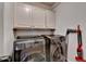Laundry room with modern stainless steel washer and dryer and ample cabinet space at 2996 Walkin Horse Trl, Buford, GA 30519
