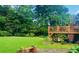 Spacious green backyard with a wooden deck, mature trees, and a decorative bench adding to the serene setting at 388 Talcott Nw Cir, Marietta, GA 30064